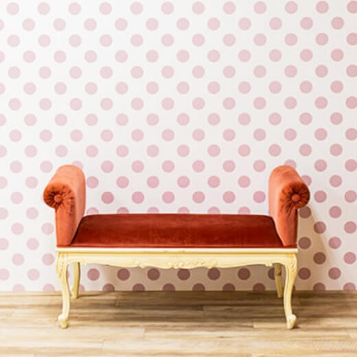ピンクの水玉模様の壁の前に赤いソファーが置かれているスタジオ