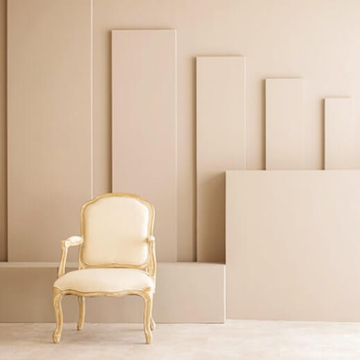 幾何学的模様の白い壁の前に白い椅子が置かれているスタジオ