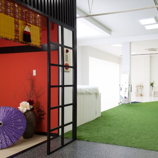 床が芝生風になっている空間と、赤い壁の畳空間があるスタジオ
