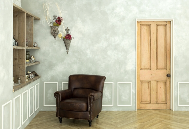 グレーの壁の部屋に木の扉と茶色のソファーが置かれた、アンティーク調なスタジオ