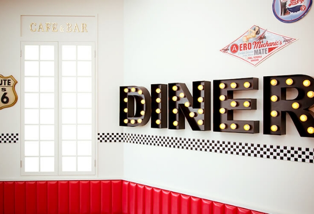 赤と白の壁に「DINER」の文字のライトが飾られているおしゃれなスタジオ